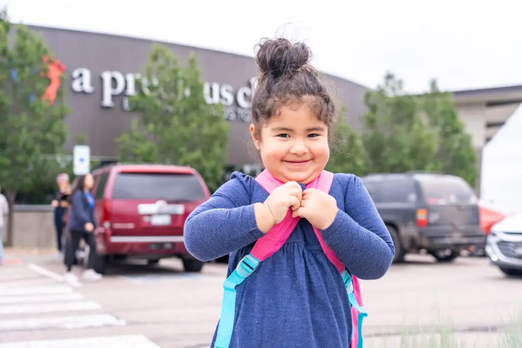 An adorable little girl smiling with her new pink backpack.