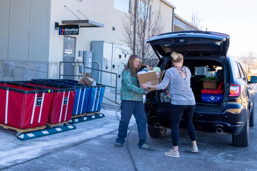 A woman handing over items from her car to an employee at the drop-off donation center.