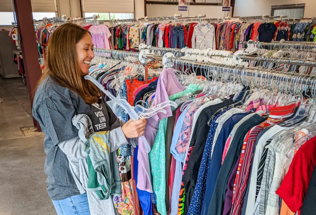 A volunteer smiling and organizing clothes for the Resource Center.