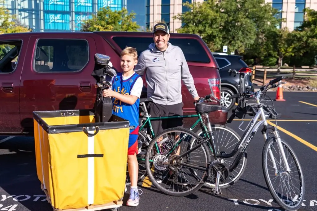 A father and son showing the bikes and golf clubs they are donating to the giveSPORTS equipment drive.