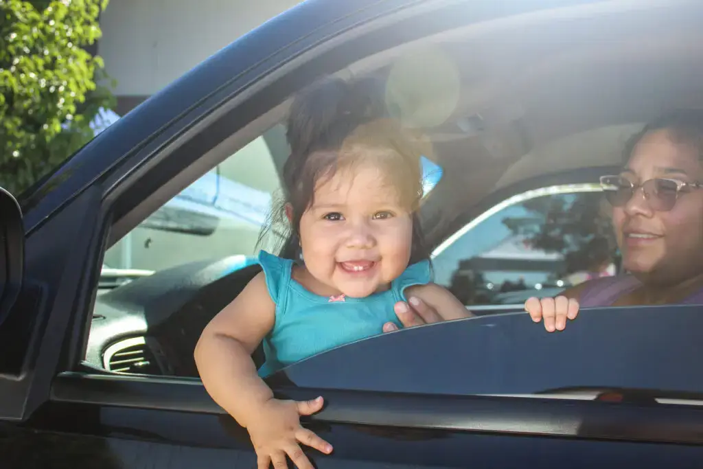 A little baby smiling from a car.
